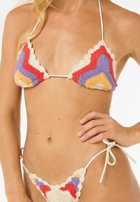 Bikini de ganchillo con copas en forma de triángulo; presenta colores rojo, púrpura, naranja y crema; bordes con volantes; lazos blancos para ajuste.