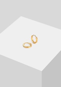 Boucles d'oreilles en or avec une surface lisse et polie, présentant un design simple et une forme arrondie. Détail de fermoir visible à l'extrémité.