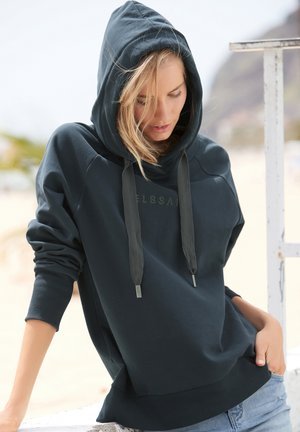 Dunkelgrüner Hoodie mit Kordelzugkapuze, gerippten Bündchen und einem Logo auf der Vorderseite. Weicher Stoff, entspannte Passform und ein Fronttaschen-Detail.