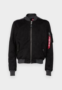 Giacca bomber nera in morbido materiale simile alla pelle scamosciata, con polsini e orlo a costine, tasca con zip e dettaglio etichetta rossa.