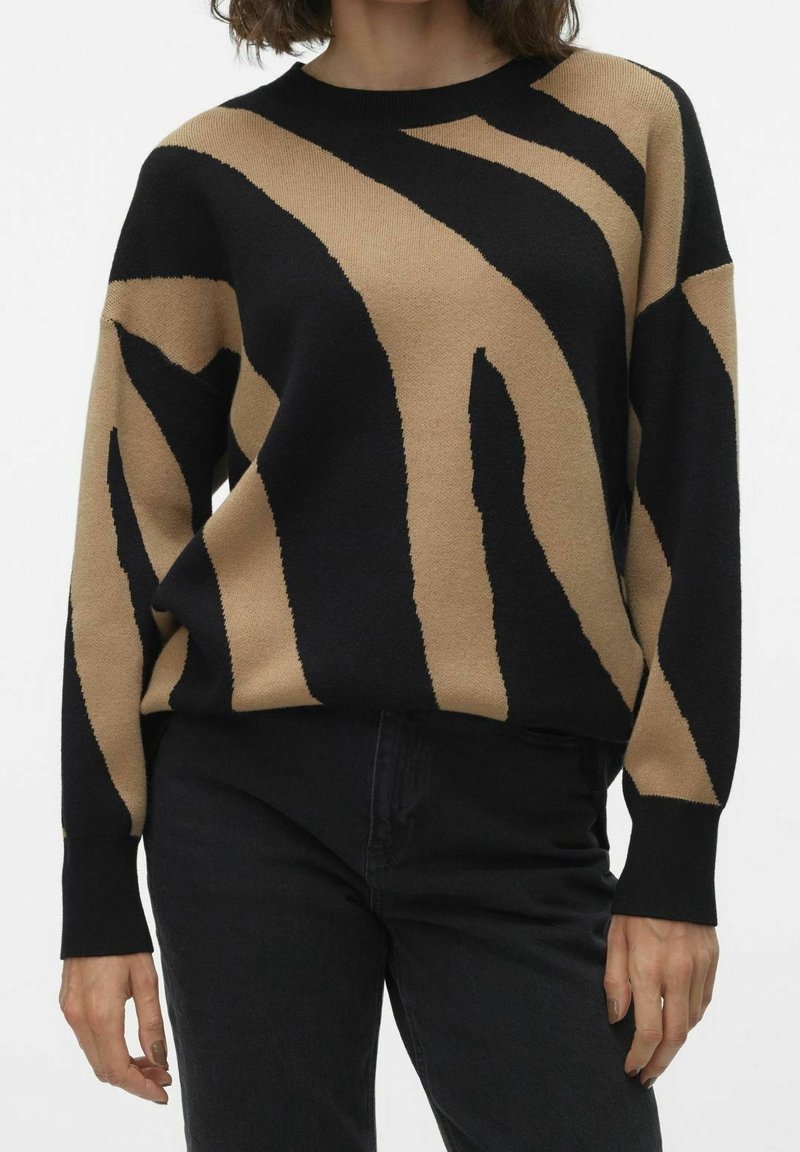 Pull tricoté rayé noir et beige avec un col rond et des manches longues, présentant une coupe décontractée et des poignets côtelés.