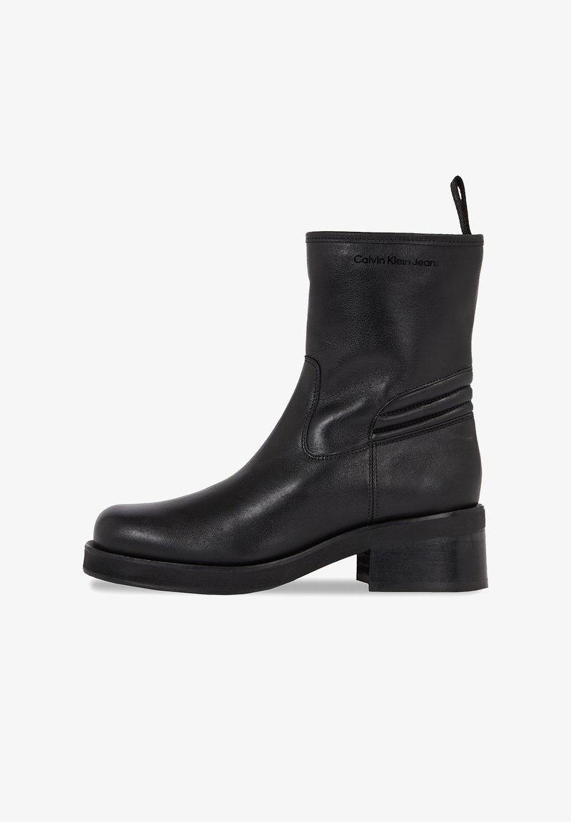 Stivaletto in pelle nera con punta tonda, tacco basso a blocco, dettaglio di cuciture laterali e linguetta sul retro. Logo "Calvin Klein Jeans" sul lato.
