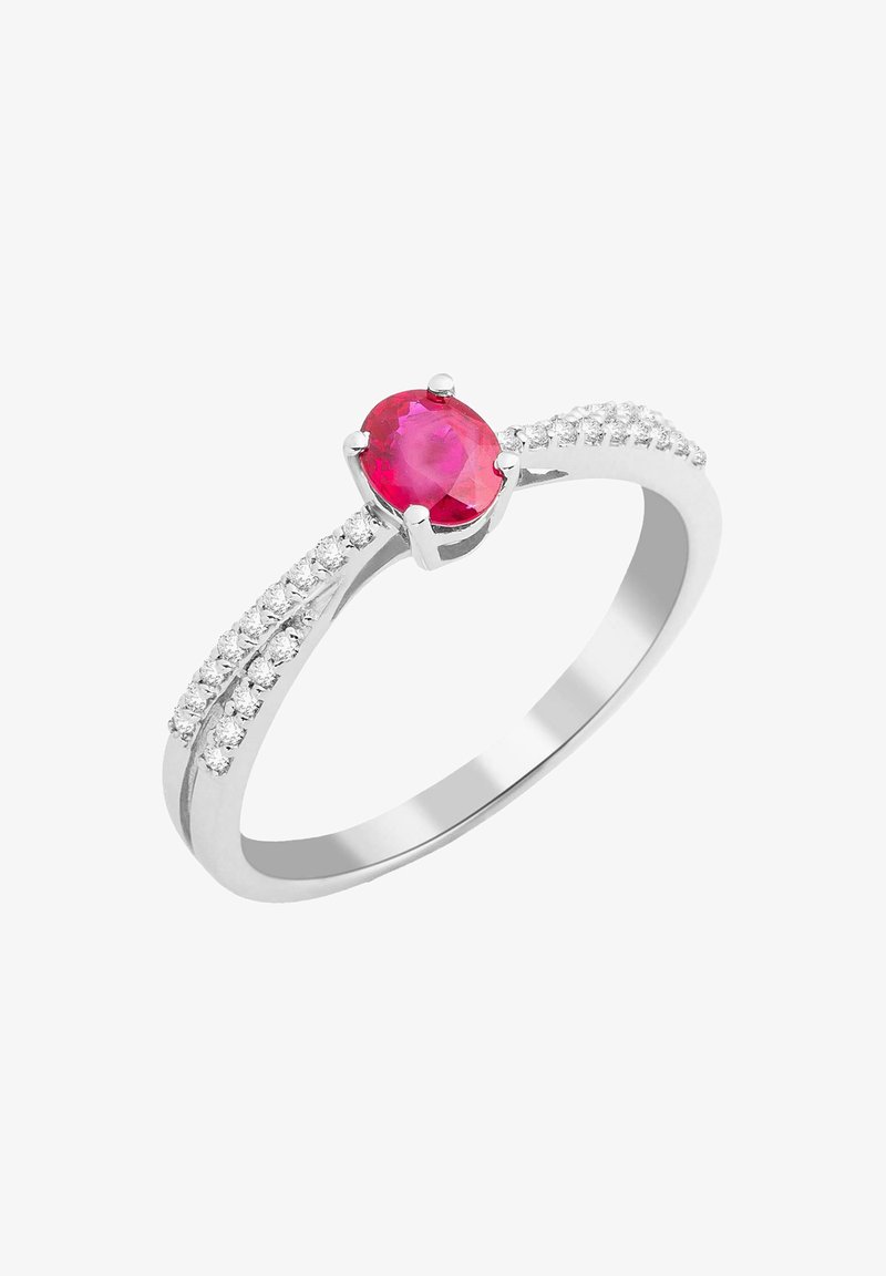 Biely kovový prsteň s oválnym červeným drahokamom, doplnený malými čírymi kameňmi po obvode pre väčší lesk.