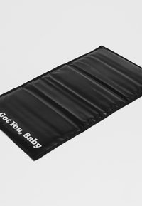 Juoda paminkštinta kilimėlis su lygiu paviršiumi ir penkiomis sekcijomis, vienoje pusėje baltomis raidėmis užrašyta „Got You, Baby“.