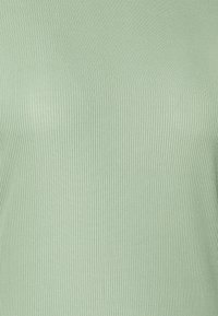 Top verde menta canalizado, feito de um material elástico, com um design ajustado e uma textura suave. Sem padrões ou detalhes de hardware notáveis visíveis.