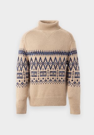 Beige strikket sweater med høj hals, der har et blåt geometrisk mønster over brystet og armene, samt ribbet manchetter og kant.