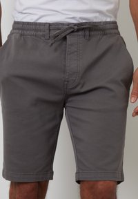 Shorts en coton gris avec une taille élastique et un cordon de serrage. Comprend des poches latérales et un ourlet piqué. Ajustement réglable avec un design décontracté.