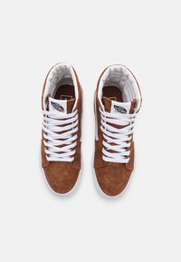 Zapatillas altas de ante marrón con cordones blancos, cuello acolchado y suelas de goma; parche con logo en la lengüeta. Superficie texturizada y detalles cosidos.