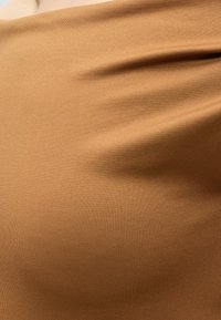 Gros plan d’un tissu brun clair lisse et tendu montrant de subtils plis et une texture.