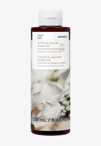 Żel pod prysznic Korres White Blossom, 250 ml, występuje w przezroczystej, cylindrycznej butelce z białą pokrywką, zdobionej białymi kwiatowymi wzorami i niebieskim napisem.