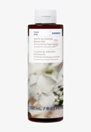 Żel pod prysznic Korres White Blossom, 250 ml, występuje w przezroczystej, cylindrycznej butelce z białą pokrywką, zdobionej białymi kwiatowymi wzorami i niebieskim napisem.