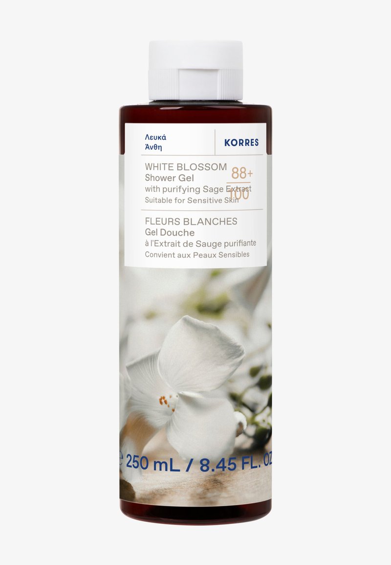 Żel pod prysznic Korres White Blossom, 250 ml, występuje w przezroczystej, cylindrycznej butelce z białą pokrywką, zdobionej białymi kwiatowymi wzorami i niebieskim napisem.