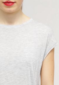 Světle šedý top s krátkým rukávem vyrobený z měkké, strukturované tkaniny s kulatým výstřihem a ohrnutými okraji rukávů. Minimalistický design bez vzorů.