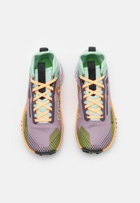 Scarpe da corsa viola e verdi con tessuto a rete, lacci arancioni e suole strutturate. Presentano un'etichetta GORE-TEX e accenti di design distintivi.