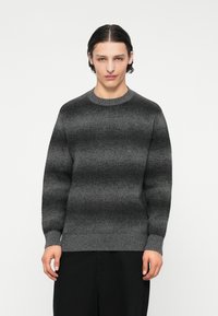 Γκρίζα ριγέ ζακέτα με στρογγυλή λαιμόκοψη και ριμπ μανσέτες. Το ύφασμα έχει απαλή υφή, με ένα gradient σχέδιο από σκούρο σε ανοιχτό γκρι.