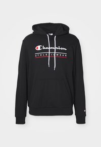 Svart hettegenser laget av myk stoff med en frontlomme, hvite snorer, og rød og hvit "Champion Athleticwear" logo på brystet.