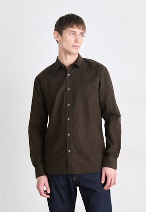 Braune Button-up-Bluse mit langen Ärmeln, gefertigt aus einem glatten Stoff. Verfügt über einen klassischen Kragen und kontrastierende Knöpfe. Getragen mit dunklen Jeans.