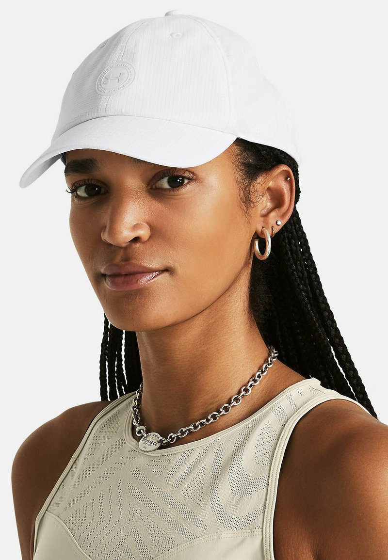 Gorra de béisbol blanca con visera curva y tejido texturizado. Presenta un parche con un logo central y detalles de costura.