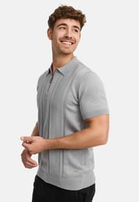 Gray knit polo shirt with a short zipper, featuring a textured herringbone pattern along the front and fitted short sleeves.