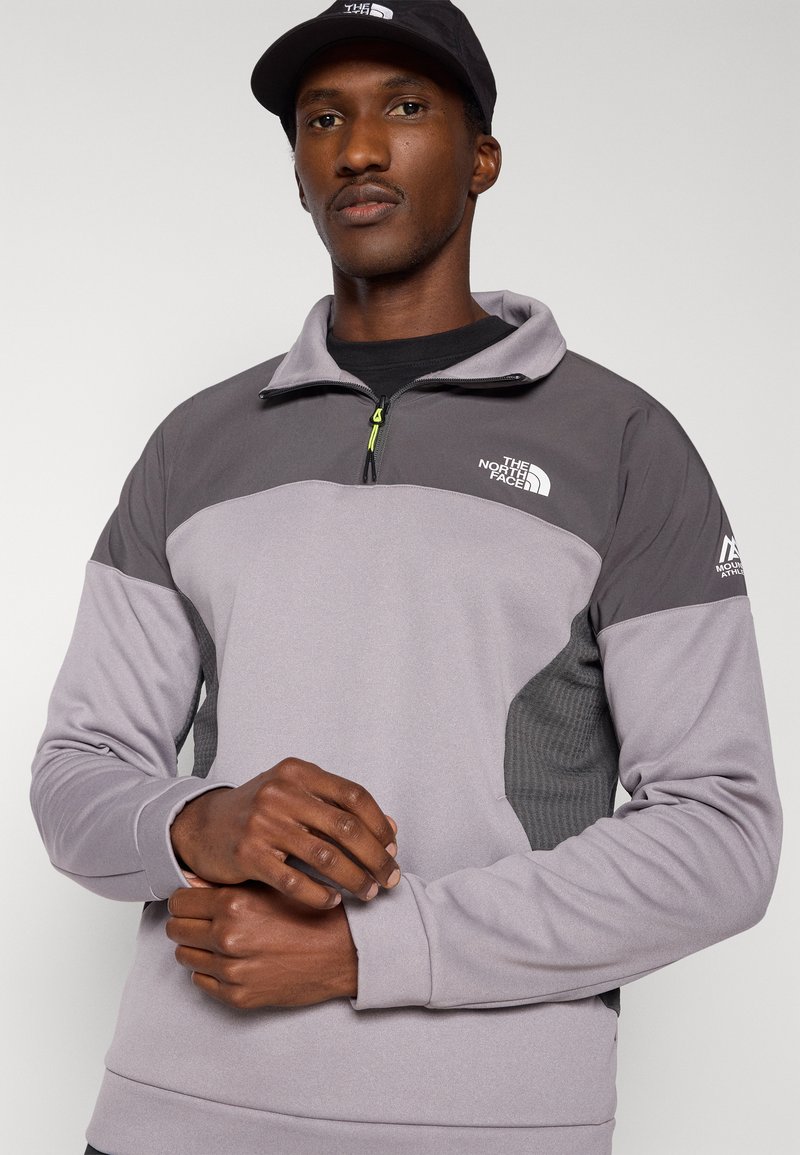 Pullover in pile grigio con design a mezza zip, caratterizzato da un pannello laterale testurizzato a contrasto e dettagli con logo sul petto e sulla manica.