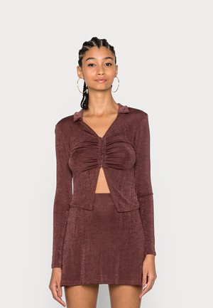 Conjunto em bordeaux de duas peças com um top cropped de manga longa com decote em V e abertura, combinado com uma saia mini ajustada.