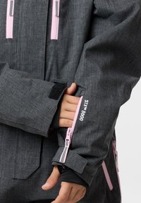 Grijze waterdichte jas met roze ritsen en details, gemaakt van textuurstof, verstelbare manchet met klittenband, en een verborgen zak.