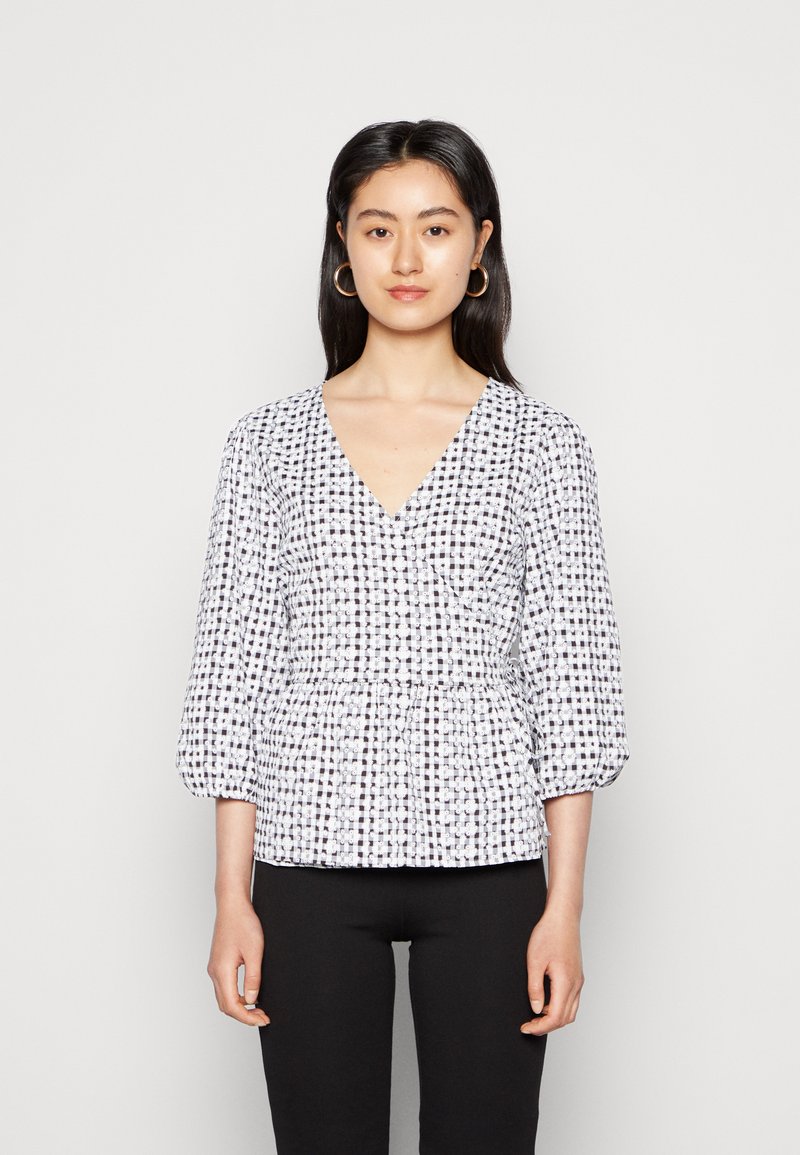 Blusa com padrão branco e preto, decote em V, mangas três-quartos e cintura franzida. O tecido parece leve, com uma textura suave.