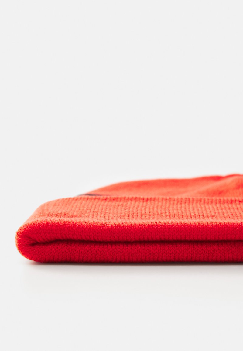 Rode gebreide beanie met een omgeslagen rand, voorzien van een textuurpatroon. Het materiaal lijkt zacht en rekbaar, geschikt voor koud weer.
