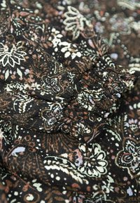 Schwarzer Stoff mit aufwendigen floralen Mustern in Braun, Weiß und sanften Pastelltönen; strukturiert, weiche Oberfläche mit geschichtetem Fall.