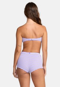 Zestaw bikini z paskowanym wzorem w kolorze fioletowym i białym. Góra w stylu bandeau z zapięciem, a dół o wysokim stanie.
