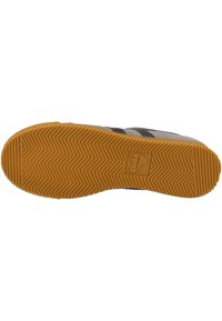 Pohja Gola-tennareissa, jossa on herringbone-kuvio, kumimateriaali ja keltaruskea väri. Logo on kohokuvioitu lähellä kantapäätä.