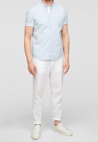 Světle modrá košile s krátkými rukávy a kostkovaným vzorem, zapínaná na knoflíky, s náprsní kapsou, kombinovaná s bílými kalhotami a bílými teniskami.