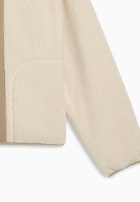 Giacca in pile di colore bianco sporco con un esterno texturizzato e soffice. Presenta un interno beige solido e una tasca laterale.