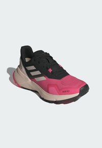 Zapatilla deportiva negra y rosa con un upper texturizado, una suela acolchada y tres franjas blancas. Presenta una puntera reforzada y cordones.