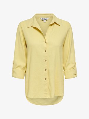 Světle žlutá košile s dlouhým rukávem, na knoflíky, s límečkem, rukávy s možností přehnutí a zaobleným spodním lemem, označena velikostí malá.