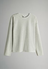 Lys grå langærmet sweater lavet af ribbet materiale. Har en rund halsudskæring og en afslappet pasform med sænkede skuldre.