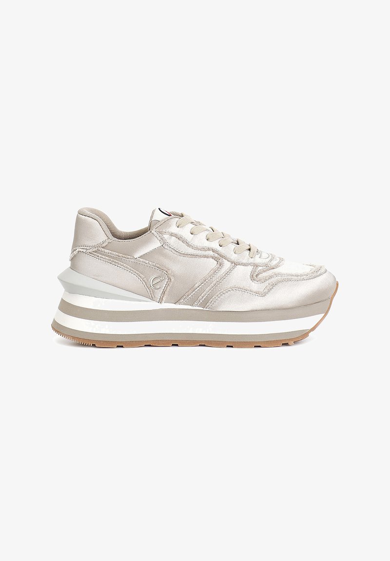 Sneaker beige clair en satin, au design arrondi, avec une semelle superposée blanche et grise, et des accents texturés sur le côté et le talon.