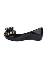 Ballerine nera in vernice con punta arrotondata, caratterizzata da un fiocco decorativo con accenti floreali dorati sul davanti. Texture liscia e design elegante.