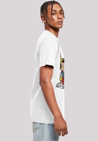 White cotton t-shirt featuring a colorful Pinocchio graphic. Short sleeves, crew neck, relaxed fit, and a casual design.