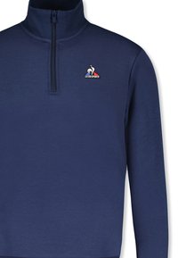 Pullover in fleece blu navy con colletto alto, zip frontale e piccolo logo ricamato sul petto. Tessuto liscio, vestibilità atletica.