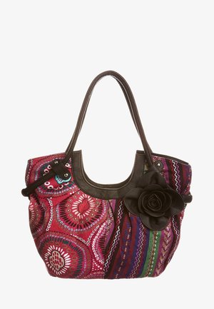 Monivärinen kangaskassi, jossa on kukkakoristelu, tummat nahkakahvat, pyöreitä kuvioita ja kirkkaat raidat, sävyissä pinkkiä, sinistä ja vihreää.