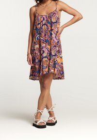 Robe fluide sans manches avec un motif cachemire multicolore, dotée de bretelles réglables et d'un ourlet volanté, associée à des sandales à lanières.