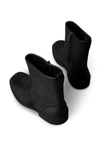 Czarne skórzane botki za kostkę o fakturowanym wykończeniu, z zamkiem błyskawicznym po boku i zaokrąglonym noskiem. Solidna czarna gumowa podeszwa.