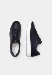 Baskets en cuir bleu marine avec un bout arrondi, semelle en caoutchouc blanche et un design à lacets. Présente des détails du logo doré sur le côté.