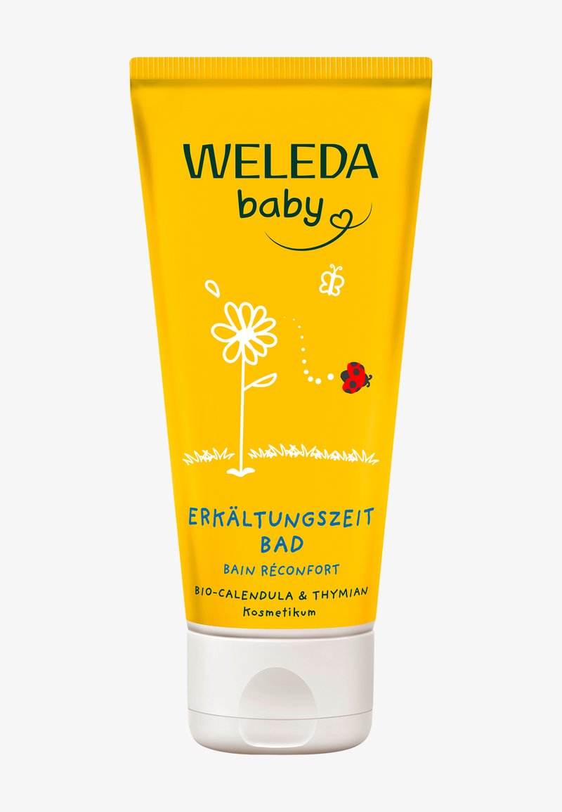 Tubetto giallo con illustrazioni di fiori bianchi e coccinelle. Il testo include "Weleda baby" e "Erkältungszeit Bad," che indicano un prodotto da bagno per bambini.