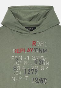 Sweat à capuche vert olive avec une capuche spacieuse. Comprend un texte imprimé en blanc, rouge et gris foncé, y compris le nom de la marque "REPLAY/DNM". Matériau en coton doux.
