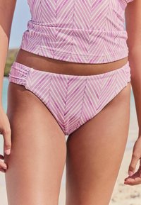 Set de bikini cu dungi roz și albe, având un design pliat pe lateral. Țesătura pare netedă, cu un ușor luciu.