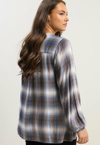 Ruudullinen paita sinisestä, ruskeasta ja valkoisesta. Ominaisuuksina pitkähihaiset hihansuut elastisilla resoreilla ja rento istuvuus. Kevyt, kudottu materiaali.