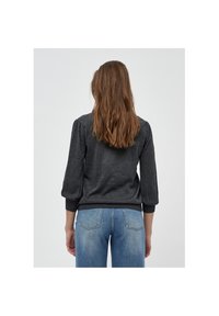 Grå stickad tröja med trekvartsärmar, texturerat tyg och ribbade ärmslut, kombinerad med ljusblå jeans med bakfickor.