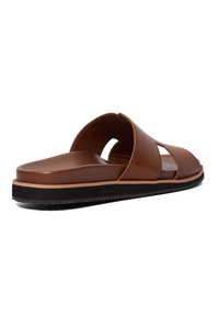 Bruine slide-sandaal met een gladde leren bovenkant, open uitsparingen, een gevormd voetbed en een contrasterende zwarte rubberen zool.